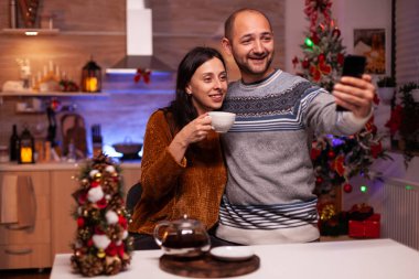 Modern akıllı telefon kullanarak selfie çekerken mutlu aile gülümsemesi.