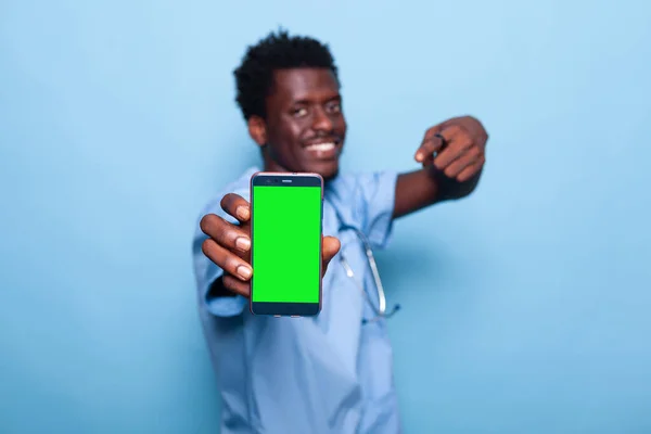 Pielęgniarka pokazuje smartfon z pionowym zielonym ekranem — Zdjęcie stockowe