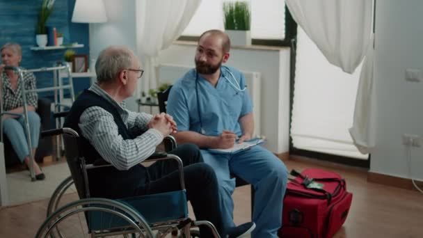 Medical assistant consulting old man with disability — Stock Video