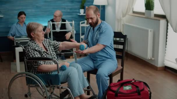 Asistente médico ayudando a mujer discapacitada con ejercicios físicos — Vídeo de stock