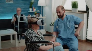 Huzurevinde video gözlüğü kullanan tekerlekli sandalyedeki engelli yaşlı kadın.