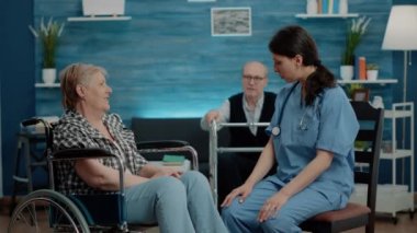 Hemşire huzurevinde tekerlekli sandalyedeki emekli kadına danışmanlık yapıyor.