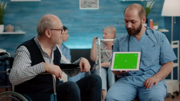 Man sjuksköterska och gammal patient tittar på grön skärm på tabletten — Stockvideo