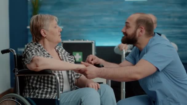 Mężczyzna pielęgniarka trzymając się za ręce i pocieszający niepełnosprawny emeryt — Wideo stockowe