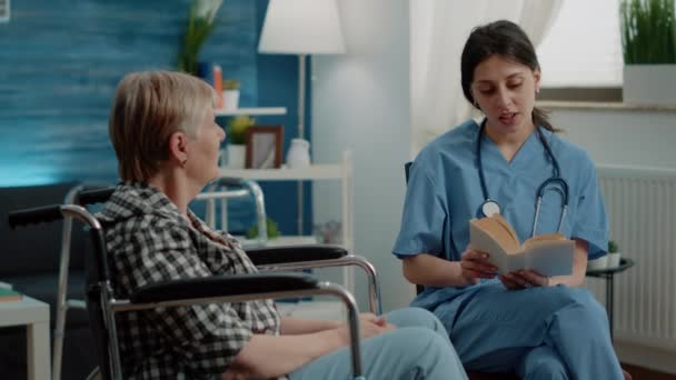 Książka do czytania asystenta medycznego dla starszej kobiety niepełnosprawnej — Wideo stockowe