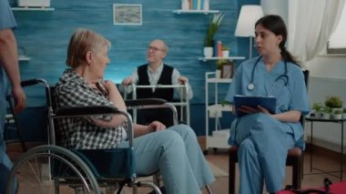 Engelli emekli kadın sağlık kontrolü için hemşireyle konuşuyor.