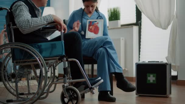 Alte Patientin mit Handicap schaut Herzfigur auf Tablet an — Stockvideo