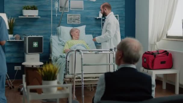 Médico y enfermera consultando a mujer jubilada acostada en cama de hospital — Vídeos de Stock
