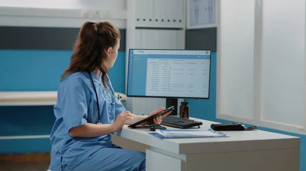 Medicinsk assistent som arbetar med dator och digital surfplatta — Stockfoto