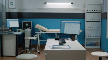 Tıbbi ekipman ve bilgisayarı olan boş bir doktor ofisi.