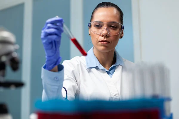 Científica mujer sosteniendo tubo de análisis de sangre trabajando en el experimento de microbiología —  Fotos de Stock