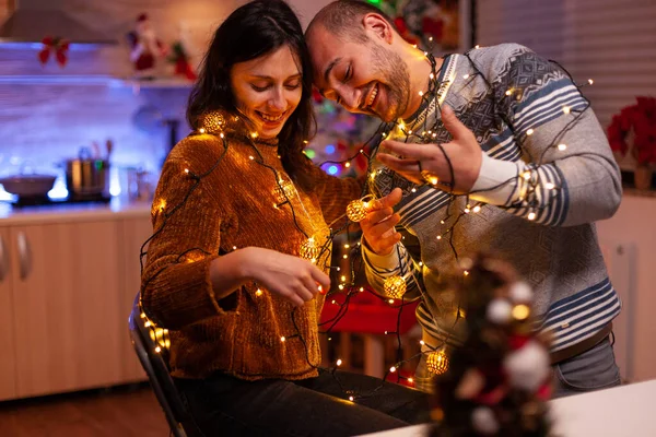 Noel ağacı ışıklandırması dekorasyon mutfağıyla eğlenen neşeli çift. — Stok fotoğraf