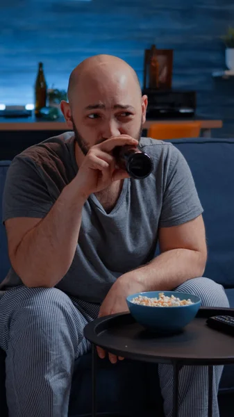 Amüsierter Mann lacht, wenn er einen Comedy-Film im Fernsehen sieht und Popcorn isst — Stockfoto