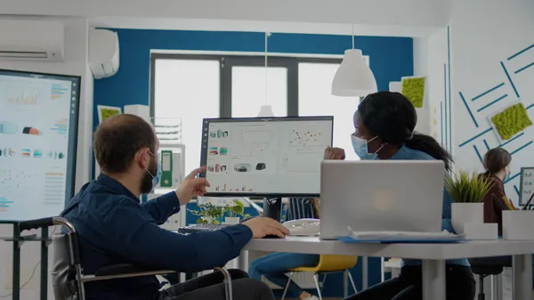 Gestionnaire africain avec masque facial travaillant avec un employé invalide dans un nouveau bureau normal — Photo