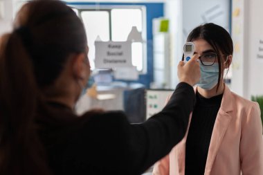 İş kadını ısıyı ölçmek için kızılötesi tıbbi termometre kullanıyor