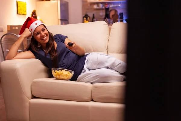 Dziewczyna leży na kanapie oglądając zimowy serial rozrywkowy w telewizji — Zdjęcie stockowe