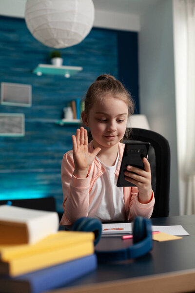 Schoolchild greeting remote friend during online videocall meeting conference