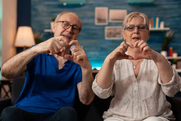 Casado casal idoso fazendo símbolo de coração com as mãos — Fotografia de Stock