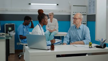 Doktor, tıbbi kabinedeki yaşlı hasta sağlık hizmetlerini kontrol ediyor.