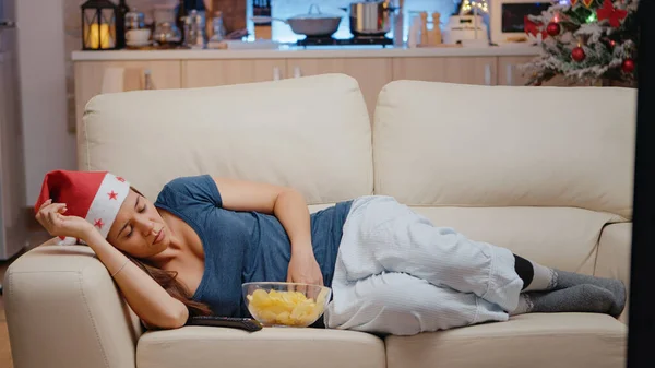Ospalá žena se Santou klobouk sledování televize na pohovce — Stock fotografie