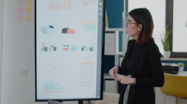 İş kadını televizyonu veri tablosuyla işaret ediyor