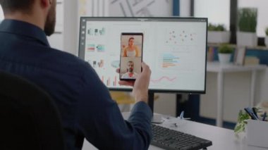 Şirket çalışanı video görüşmesi için akıllı telefon tutuyor.