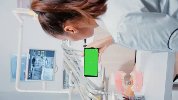 Vertikal video: Specialist analysera mobiltelefon med grön skärm — Stockfoto