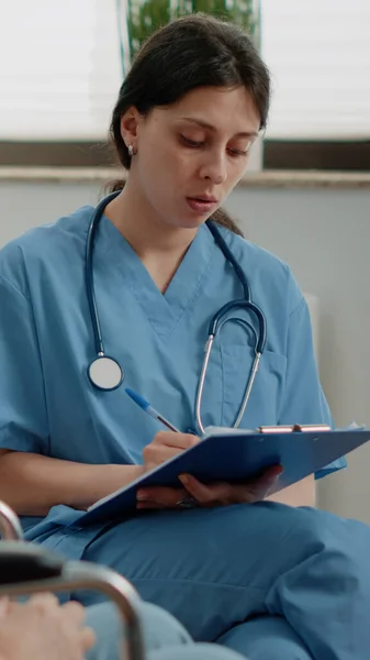 Жінка-медсестра вивчає охорону здоров'я пацієнта у відставці — стокове фото