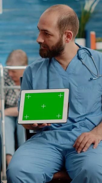 Man sjuksköterska och gammal patient tittar på grön skärm på tabletten — Stockfoto