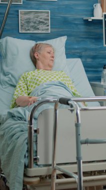 Hemşire huzurevinde hastalıklı emekli bir hastayla konuşuyor.