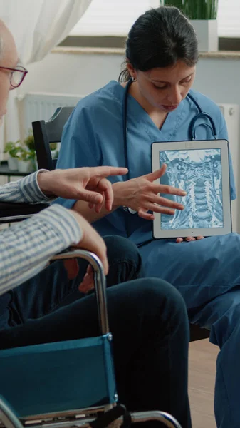 护士在平板电脑上向人类解释骨病X光 — 图库照片