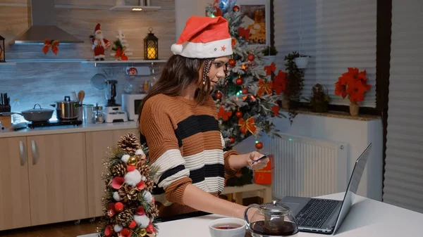 Mladá žena se Santa klobouk dělá on-line nakupování — Stock fotografie