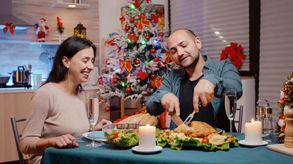 Homem cortando frango para mulher no jantar festivo na véspera de Natal — Fotografia de Stock