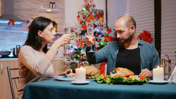 Couple clinking glasses of champagne at christmas dinner — Stock Photo, Image