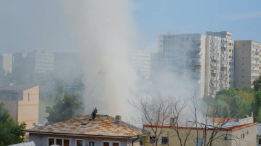 İtfaiyeciler yangını söndürmek için çatıya çıkıyorlar.