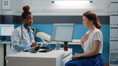 Doktor muayene kağıtları ve hasta hastalarla konuşma hakkında notlar alıyor.