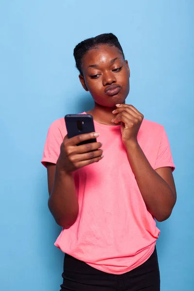 Retrato de una joven afroamericana charlando con un amigo usando un teléfono inteligente — Foto de Stock