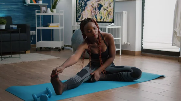 Flessibile in forma donna nera facendo stretching routine sulla mappa yoga — Foto Stock