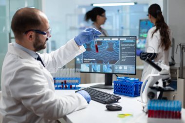 Biyoloji araştırmacısı elinde kan testi tüpü tutarak virüs uzmanlığını analiz ediyor.