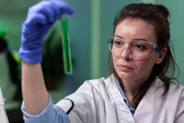 Biologa donna medico in possesso di provetta medica con soluzione di DNA verde — Foto Stock