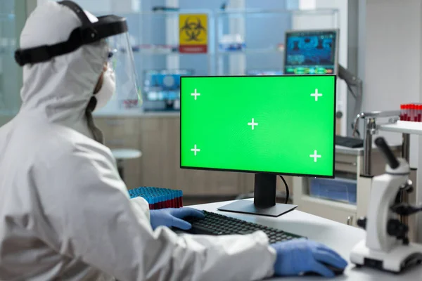 Биолог в медицинском скафандре смотрит на мак с зеленым экраном — стоковое фото