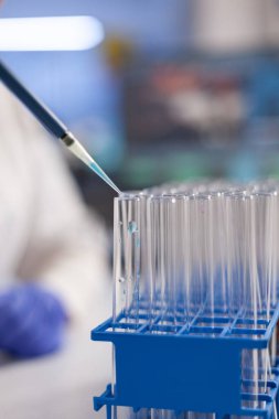 Şeffaf test tüplerinde çözeltiyi bırakan kimyager yakınlaşması