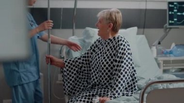 Hemşire yaşlı hastaya yürüme konusunda yardım ediyor.