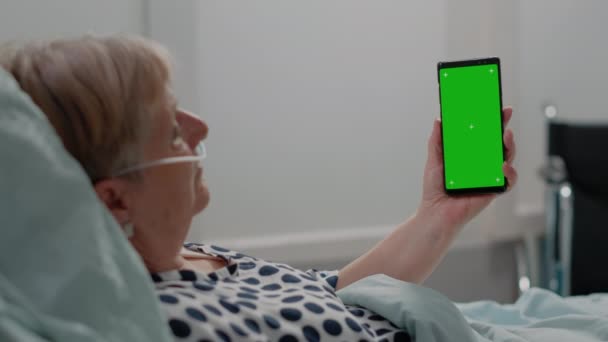 Närbild av sjuk patient vertikalt håller grön skärm på smartphone — Stockvideo