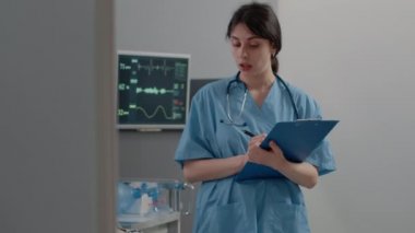 Hemşire hasta muayene için tıbbi dosyalar hakkında notlar alıyor.