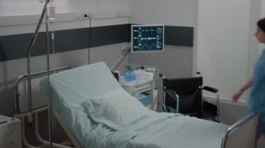 Hemşire, hastane koğuşunda sağlık ekipmanlarıyla yatak yapıyor.