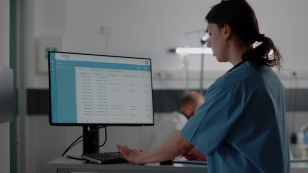 Закрытие женщины-медсестры, работавшей за компьютером в больничной палате — стоковое видео