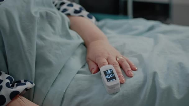 Close-up de oxímetro na mão do paciente sênior deitado na cama — Vídeo de Stock