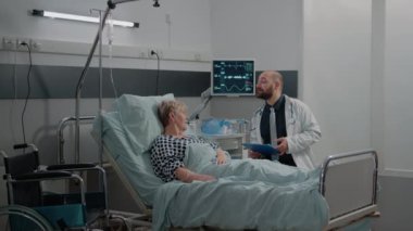 Doktor yaşlı bir hastayla hastalık ve tedavi hakkında konuşuyor.