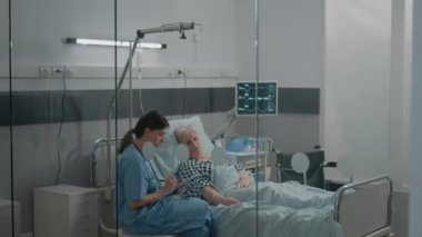 Hastane koğuşundaki hasta için sağlık asistanı muayene yapıyor.
